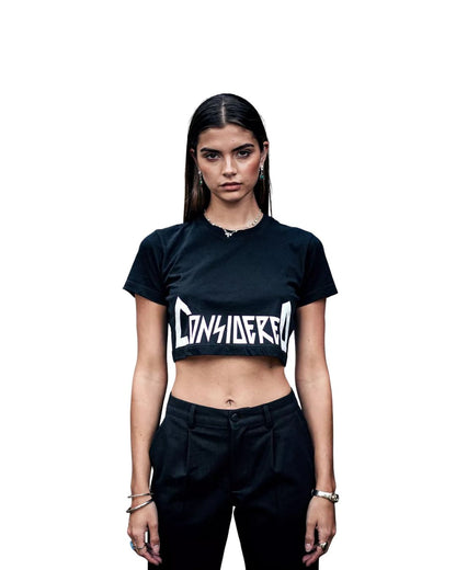 Person wearing a black crop top with 'CONSIDERED' text on a white background