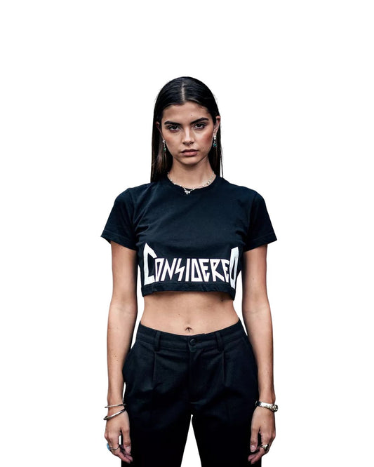 Person wearing a black crop top with 'CONSIDERED' text on a white background