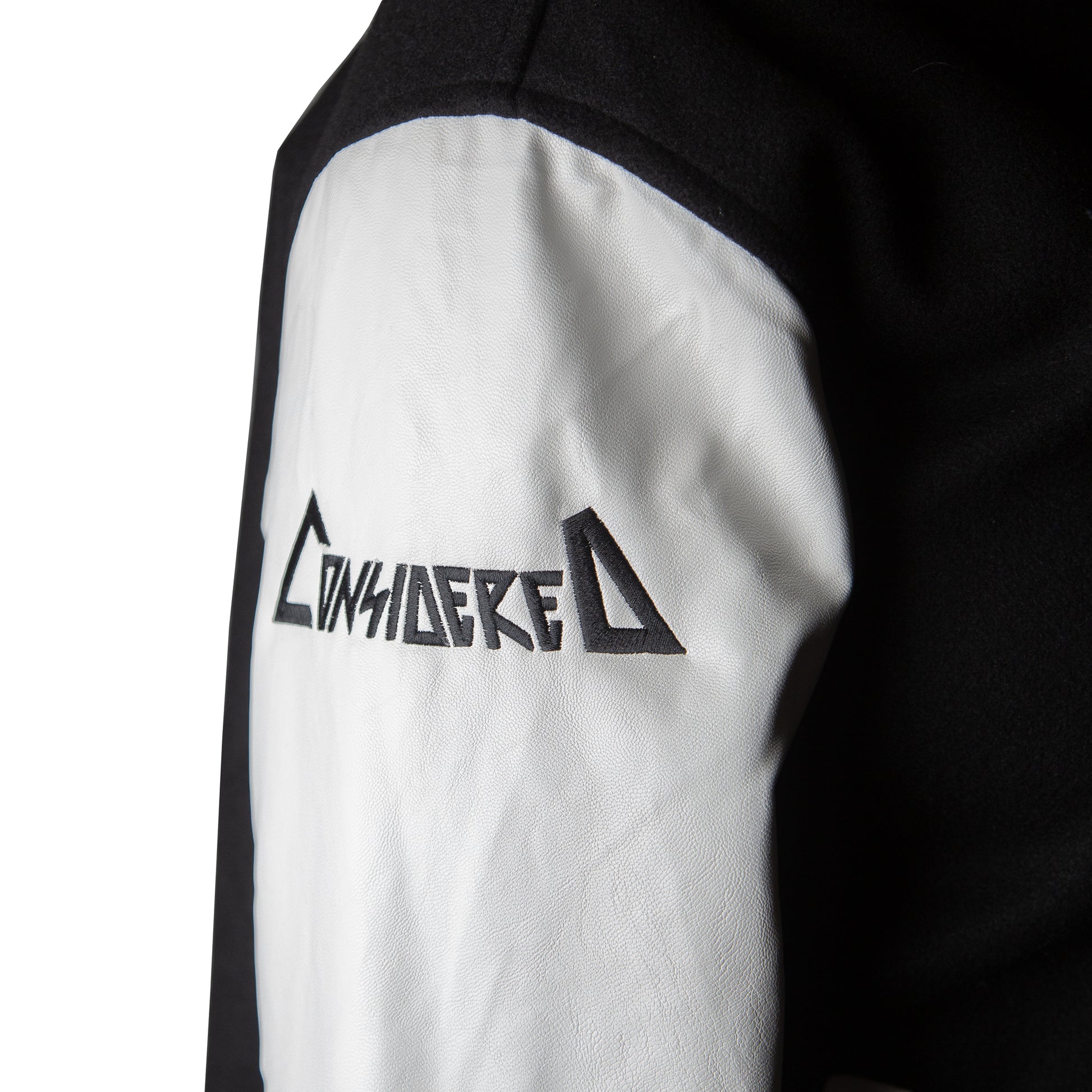 A letterman jacket with a black wool body and white faux leather sleeves. It features the 'Reaper' embroidered on the upper left chest and the words 'Considered Dead' beneath it on the back.
