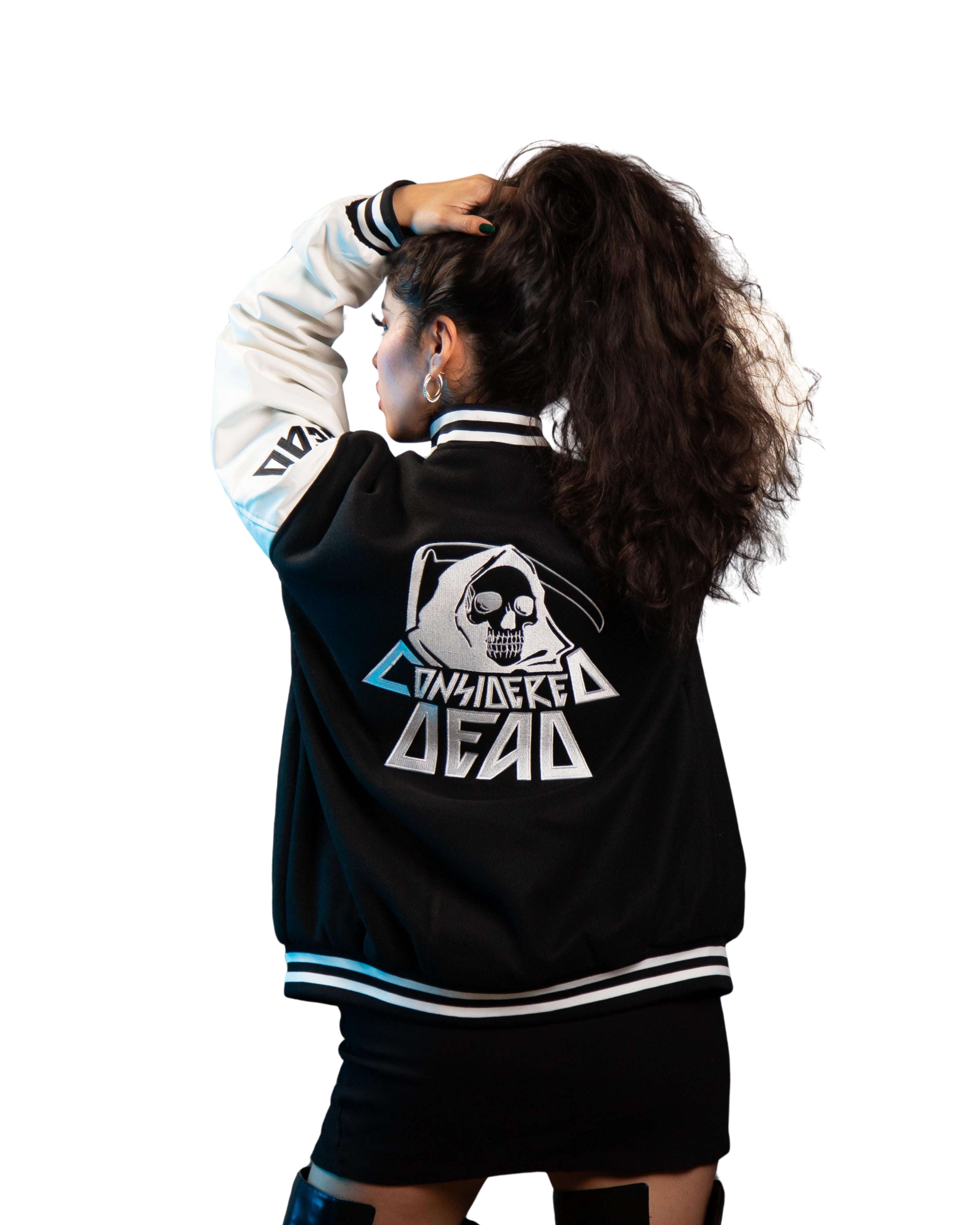 Female wearing a black and white lettermen jacket with a reaperl design and text, standing against a white background